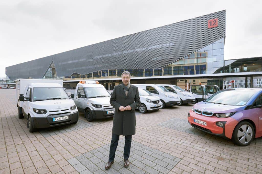 Uwe Behm, Geschäftsführer der Messe Frankfurt, und der messeinterne Fuhrpark an Elektrofahrzeugen. Darunter vertreten die Transportfahrzeuge des Typs StreetScooter und ein BMW i3.